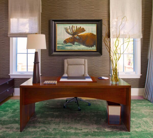 A desk with a chair and lamp in front of a painting.
