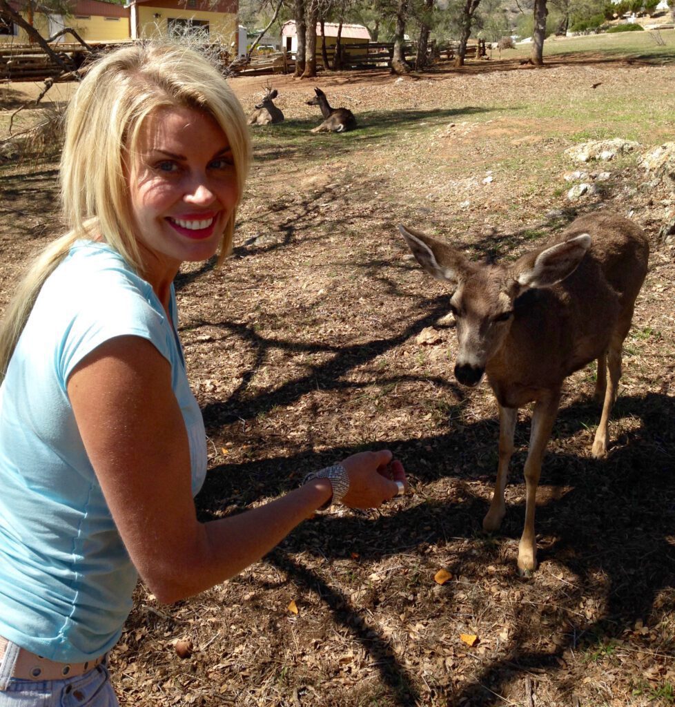 A woman feeding an animal in the dirt.