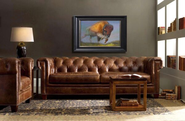 A brown leather couch in front of a painting.